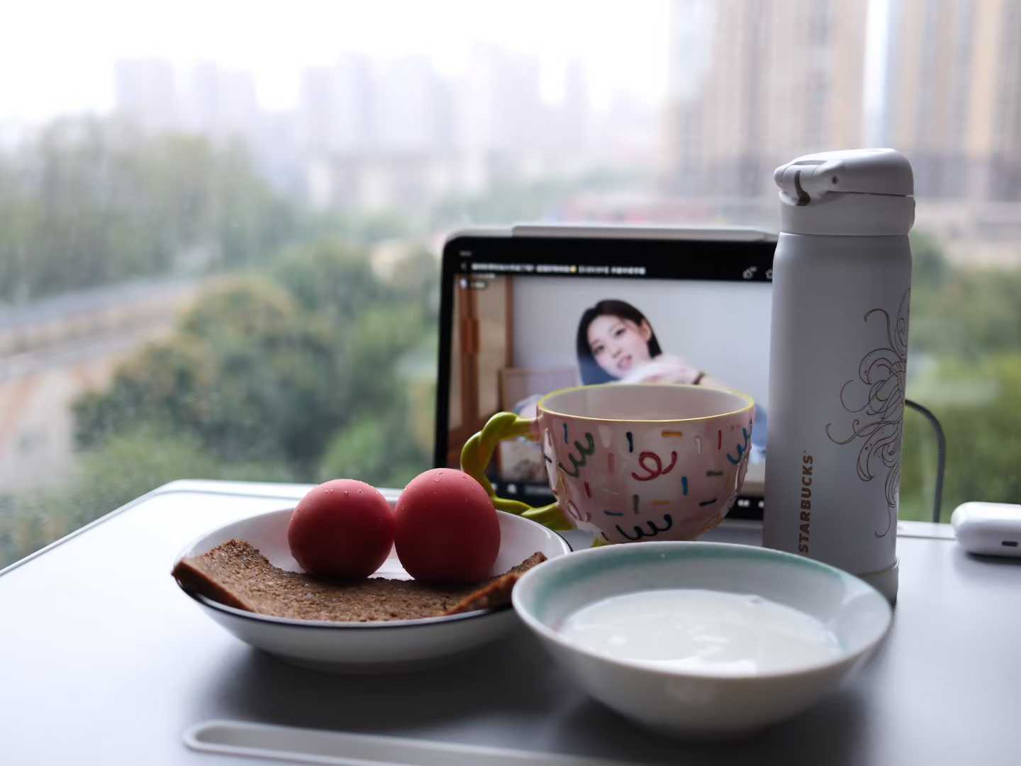 窗边桌面上的早餐、杯子和电脑